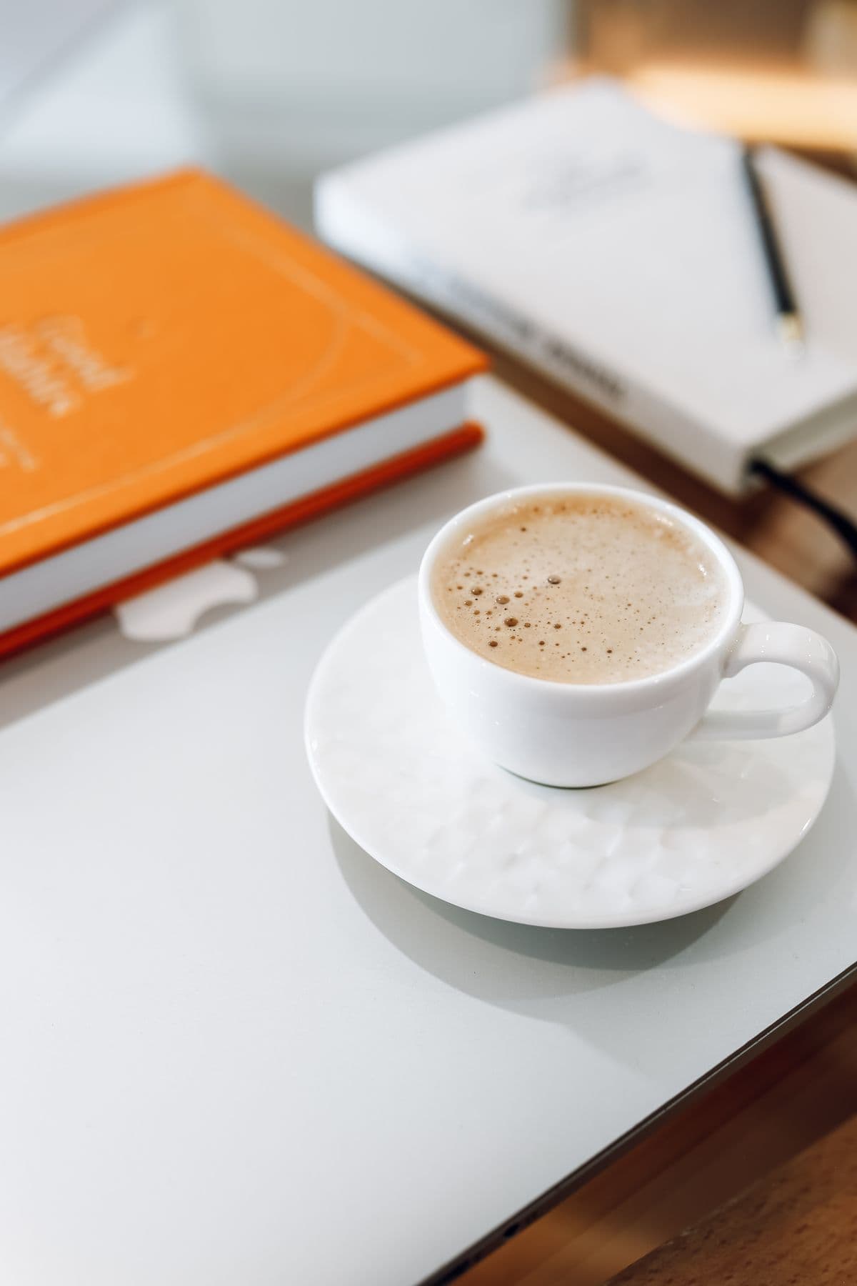 A cup of coffee beside open notebooks on a writing desk