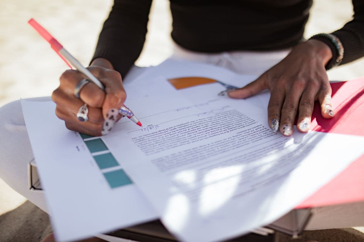 Hands marking up a printed document with a red pen